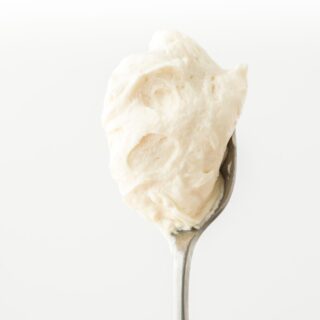 A spoon of hard sauce being lifted in a white background