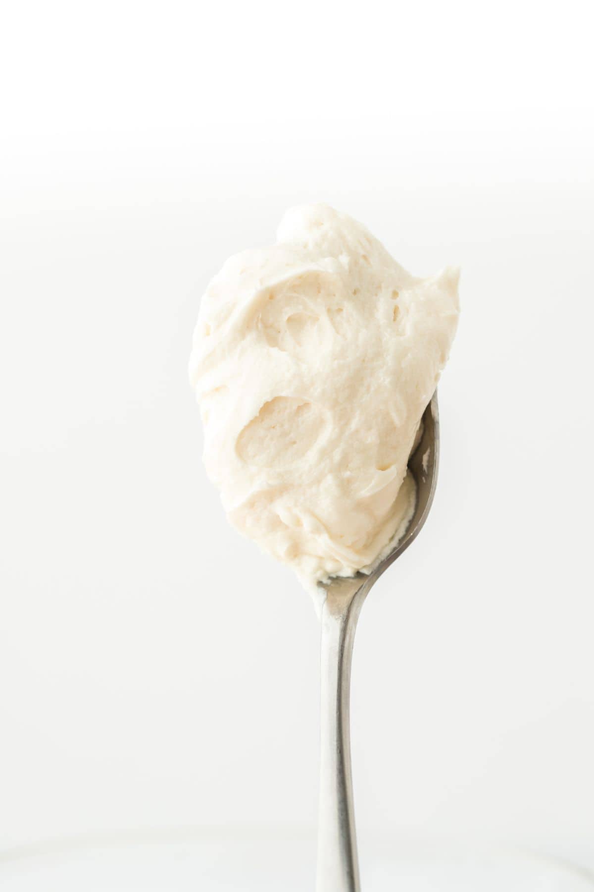 Close up of a spoon with a dollop of thick, creamy hard sauce clinging to it