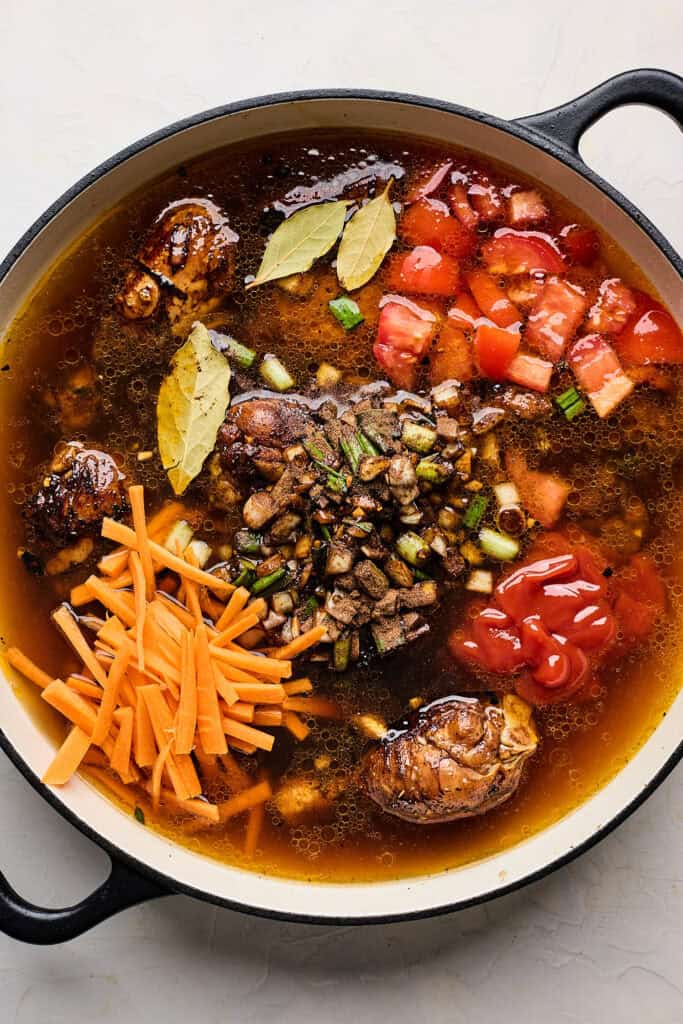 Marinade, carrots and herbs added to brown stew in a pot