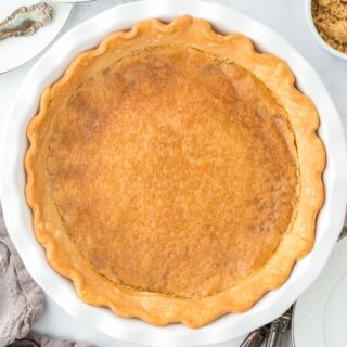 Overhead shot of golden brown vinegar pie on a white pie dish