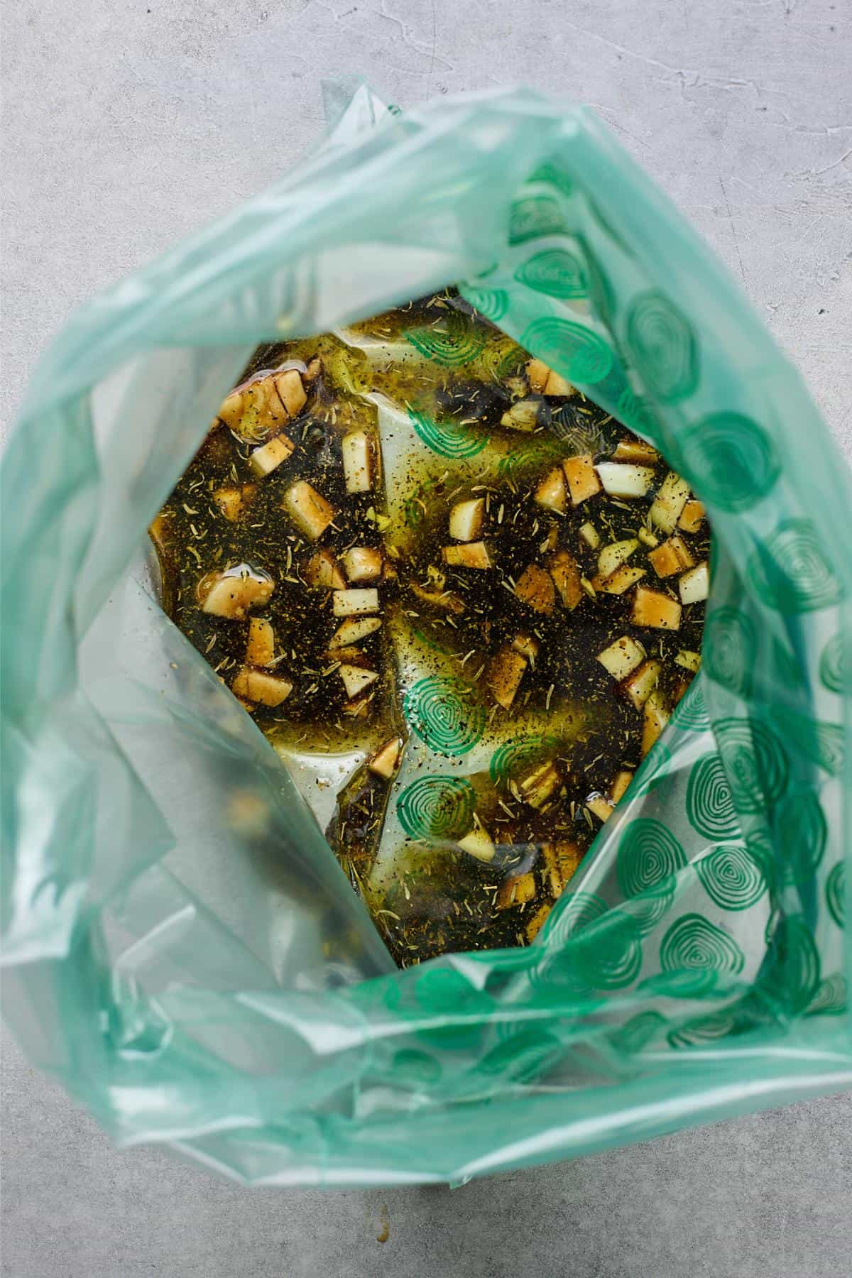 A plastic bag filled with the marinade, including chunks of garlic and seasonings