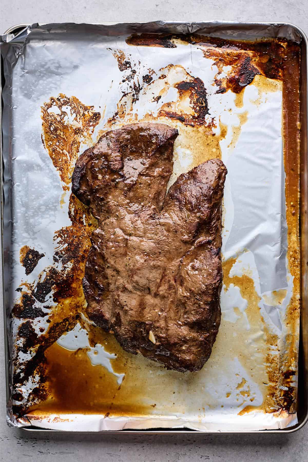 Cooked steak on baking sheet