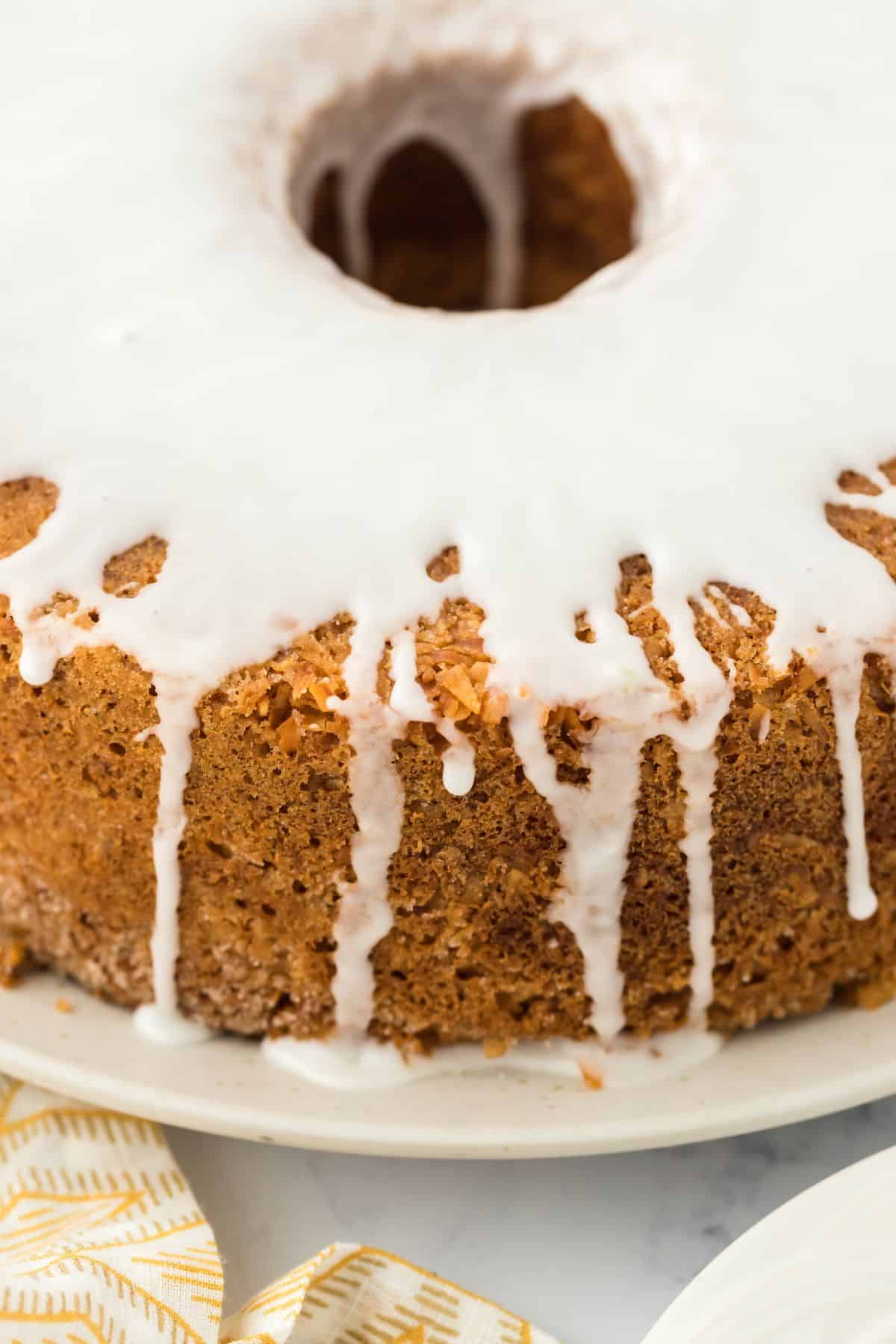 Closeup of Louisiana Crunch Cake on a white plate showing the white glaze dripping down the sides