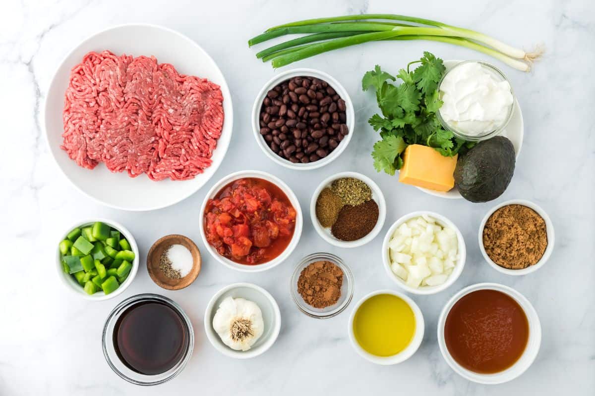 Overhead shot of ingredients to make sheet pan chili on a white surface before cooking