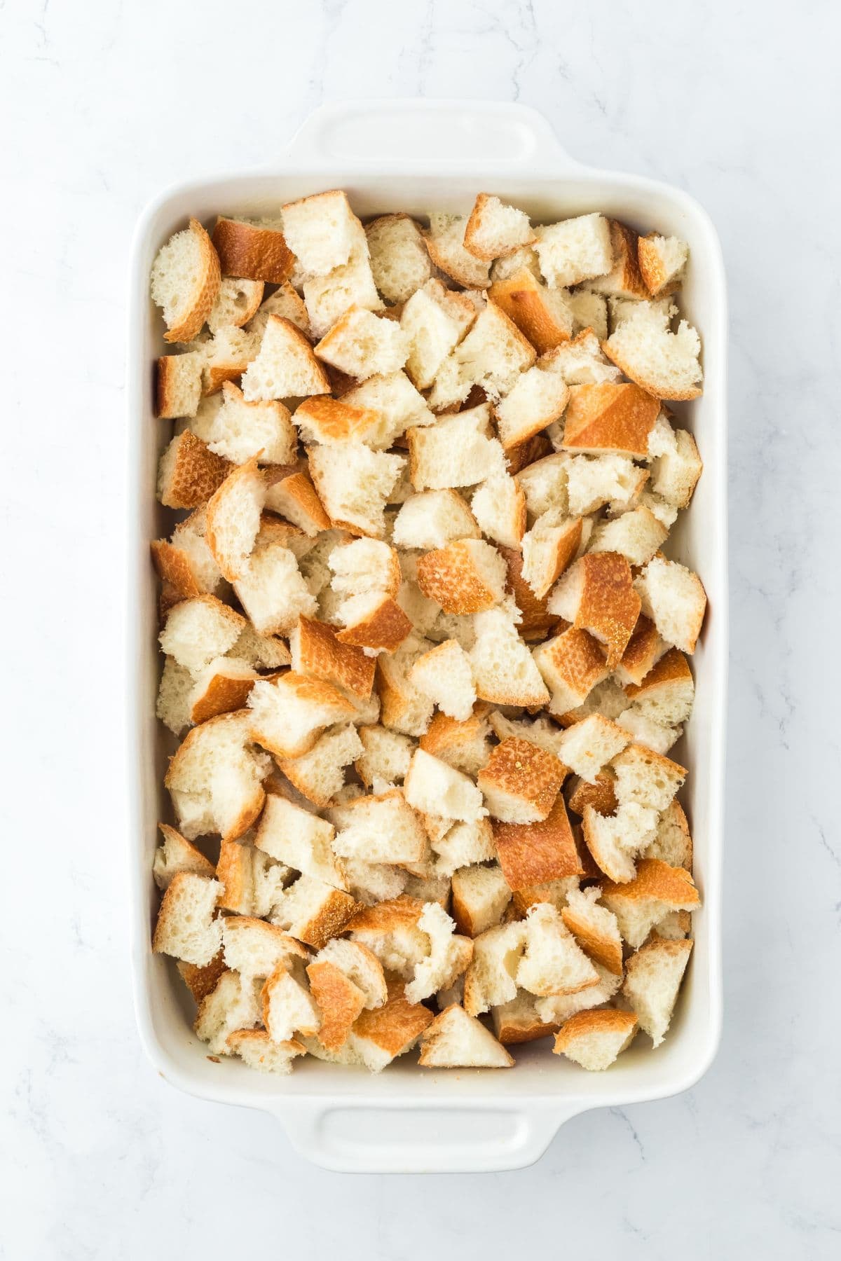 Overhead shot of cubed bread in a baking dish for white chocolate bread pudding