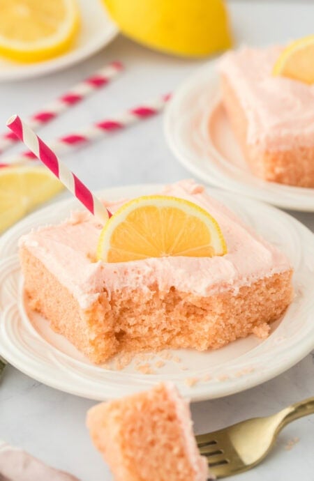 pink lemonade cake slice on a white plate with fork cutting through
