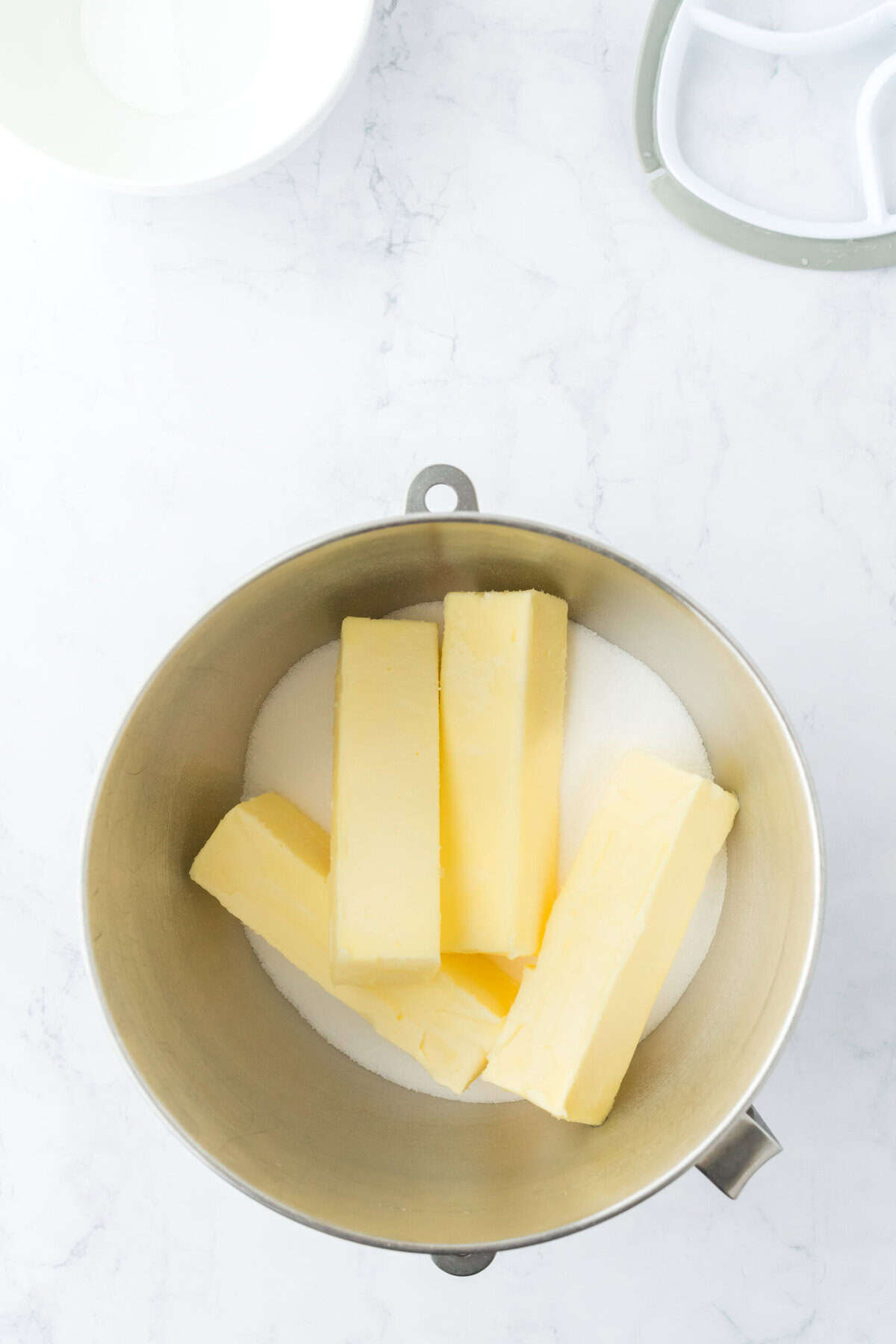 Butter and sugar in a stand mixer bowl on white countertop