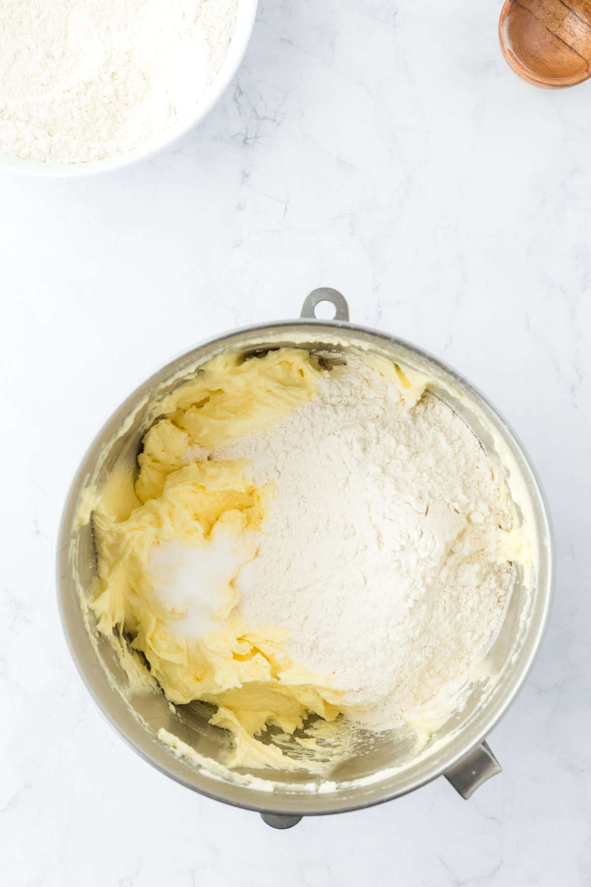 Flour mixture added to a stand mixer with pound cake batter on white countertop