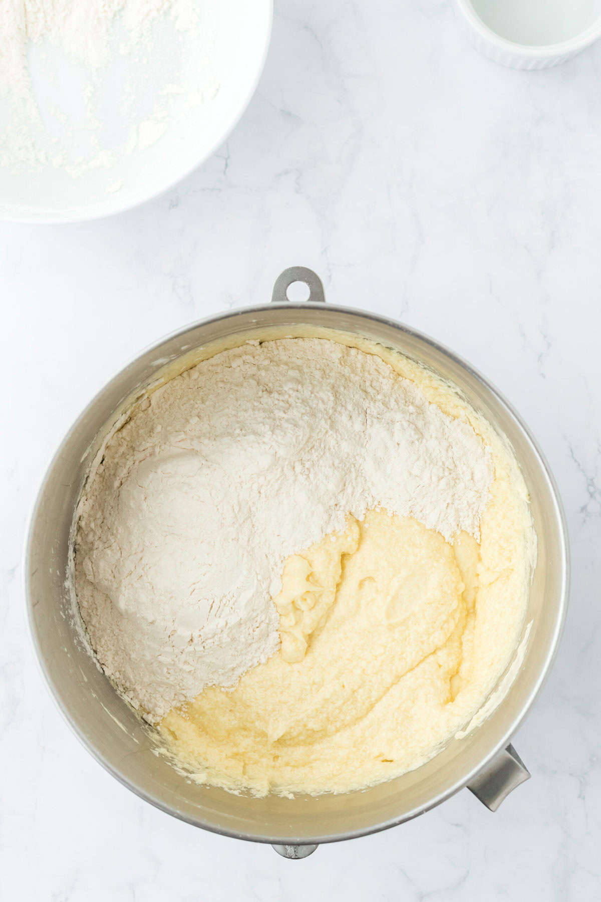 Flour added to finish up pound cake batter on white countertop