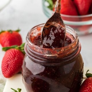 A spoon in a jar of homemade strawberry preserves