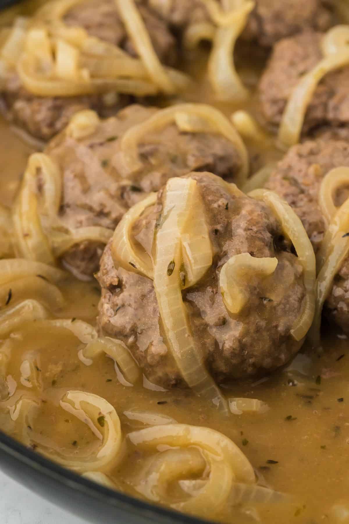 Closeup of hamburger steaks covered in a thick onion gravy