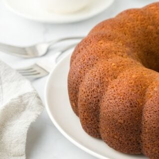 A rum cake on a white plate on a white background