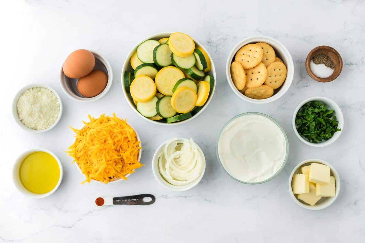 Overhead shot of ingredients to make squash casserole on a white marble surface before cooking
