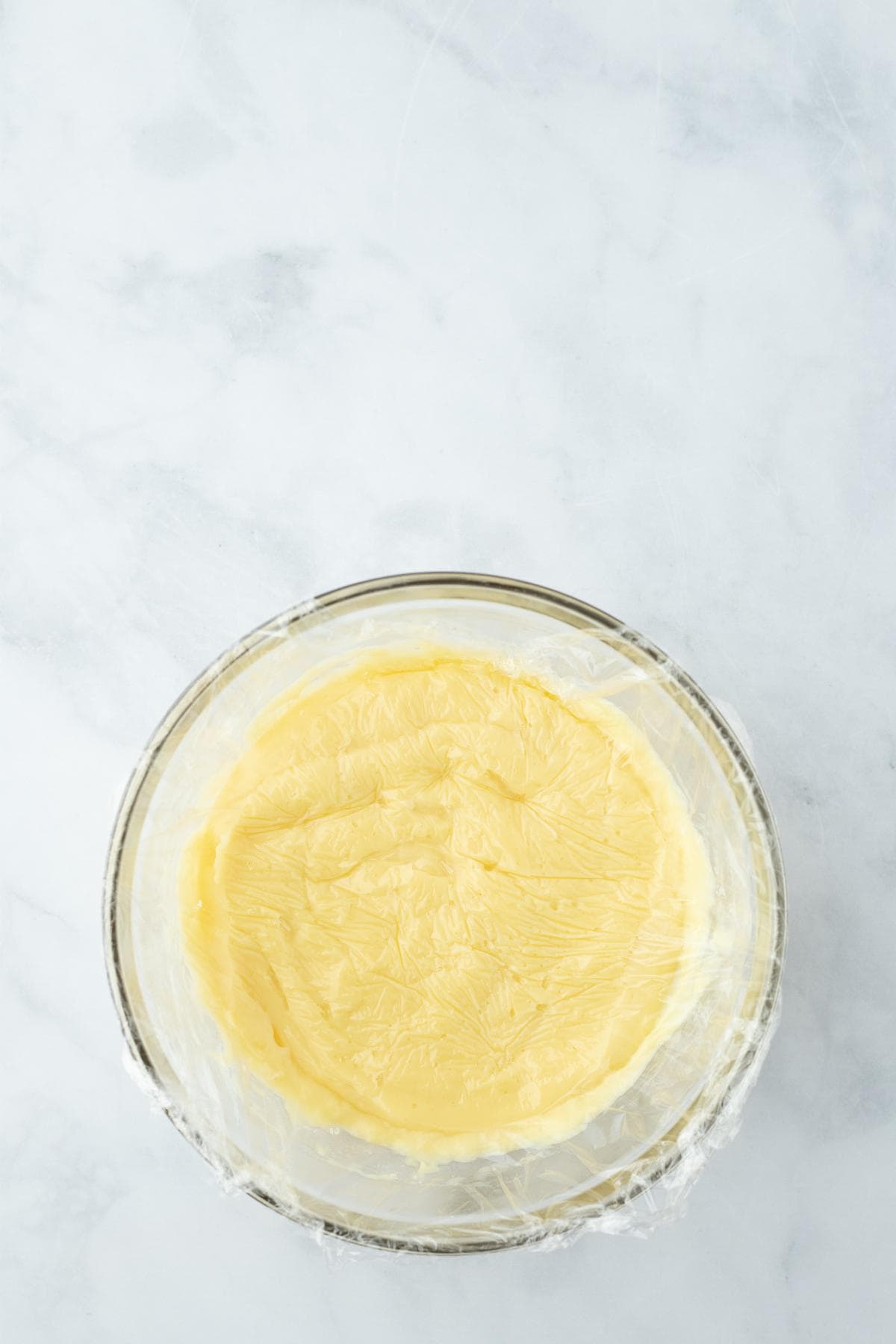 Thickened custard in a bowl covered directly with plastic wrap for strawberry custard pie