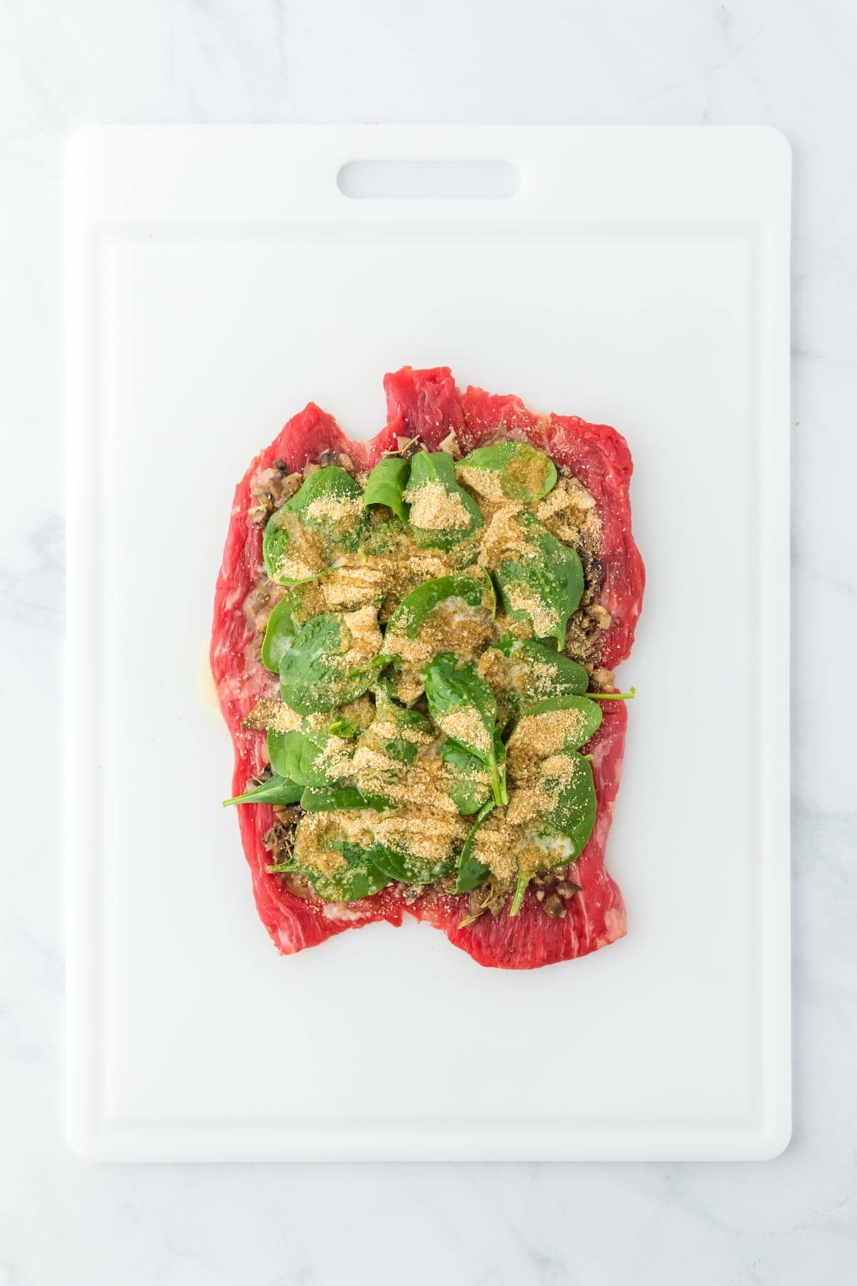 Flank steak topped with fresh spinach and breadcrumbs layered over the mushroom mixture
