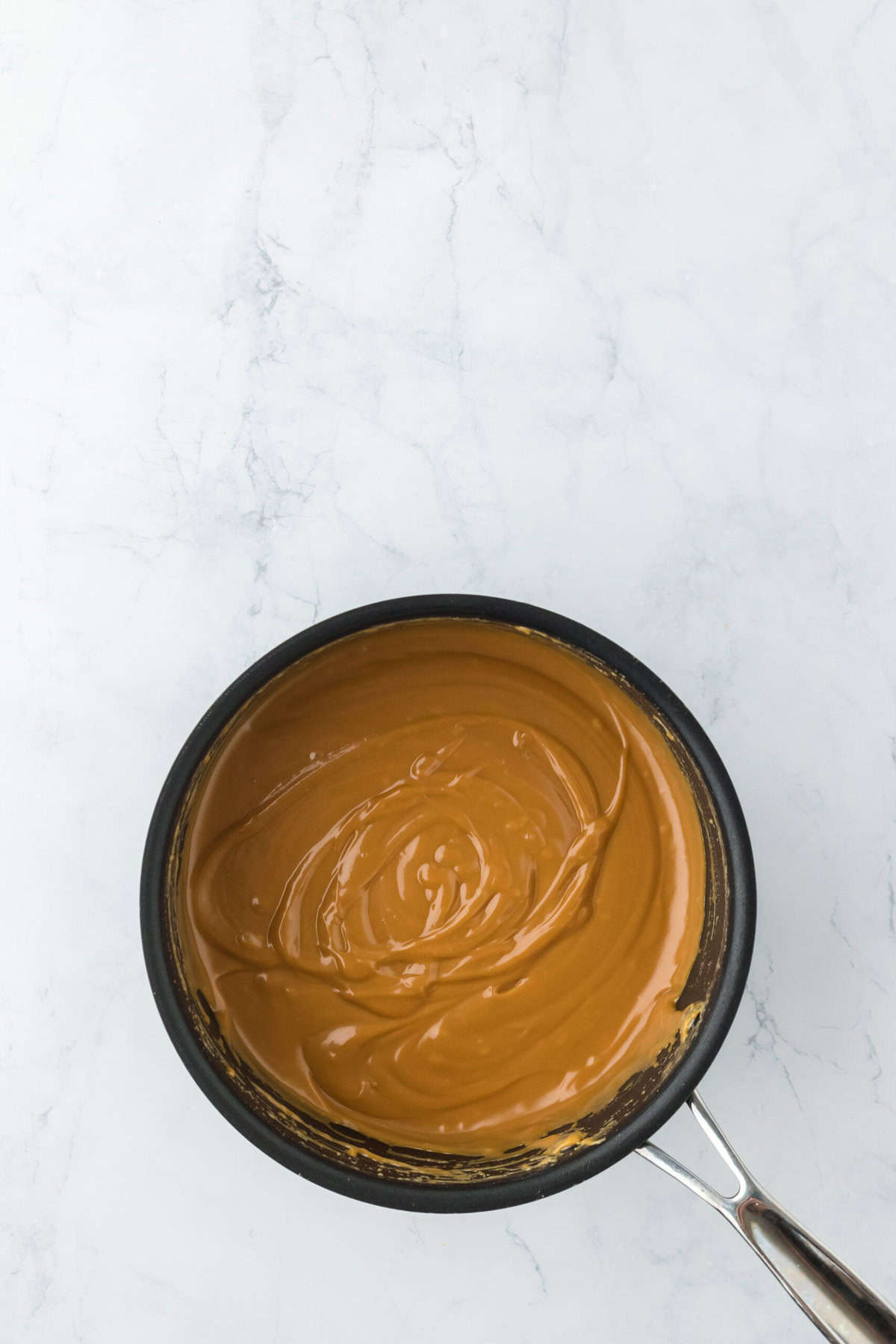 Finished caramel icing on stovetop after cooking on white countertop