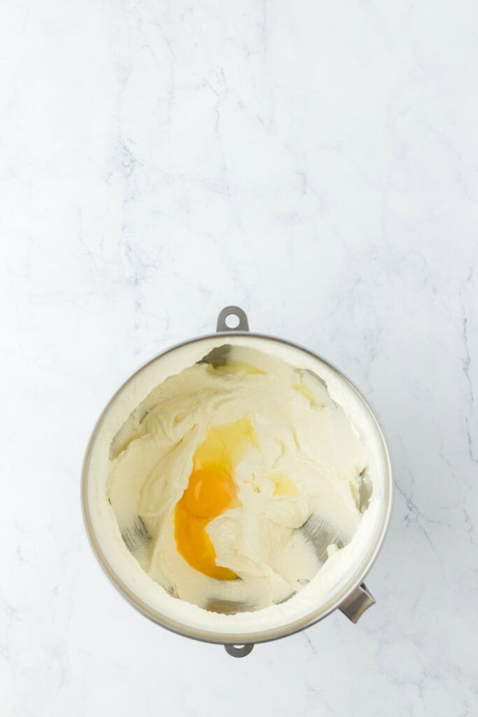 Eggs being added to cake batter on white countertop