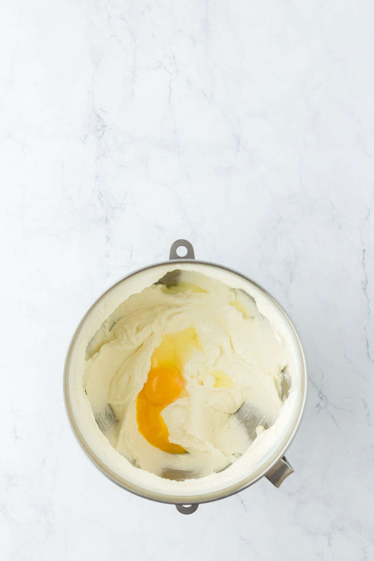 Eggs being added to cake batter on white countertop