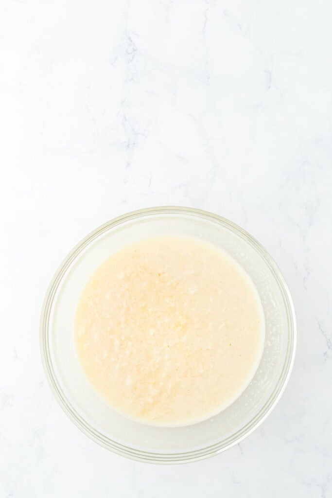 Mixed together coconut custard filling in glass bowl on white countertop