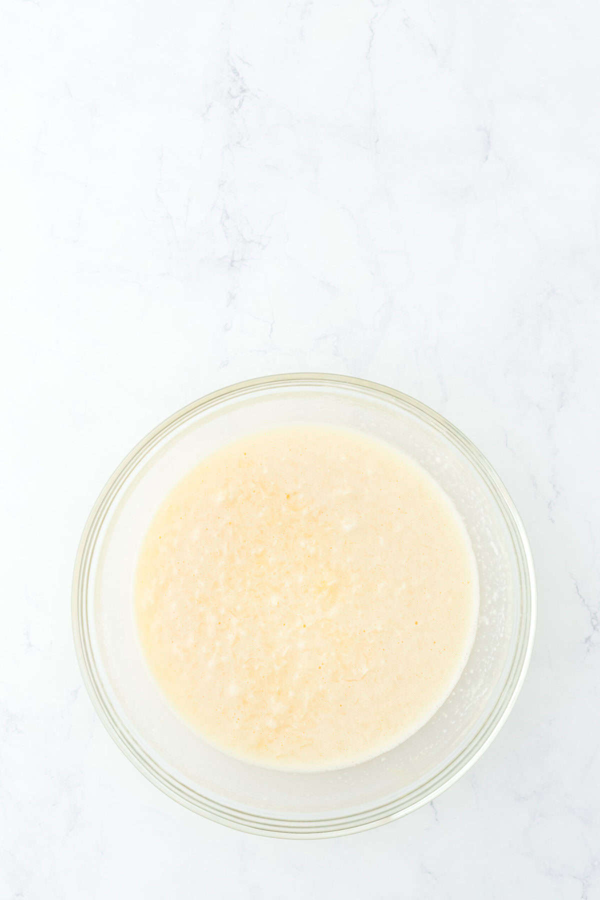 Mixed together coconut custard filling in glass bowl on white countertop