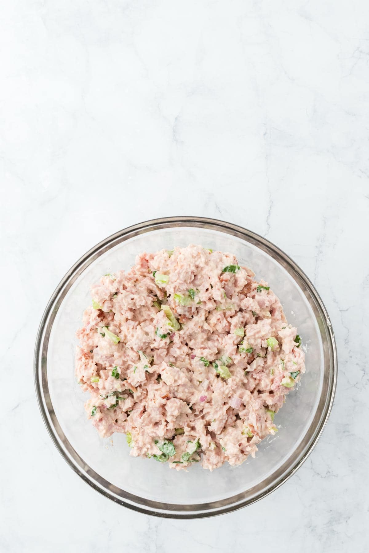 Fully mixed deviled ham  in a glass bowl, showing a creamy texture with visible bits of celery and onion