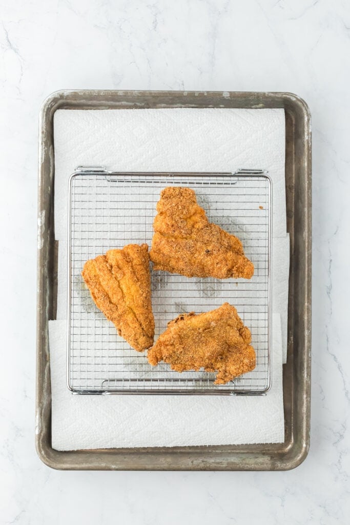 Draining fried catfish on wire rack with paper towel underneath