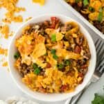 Frito pie in a white bowl with a casserole in the background
