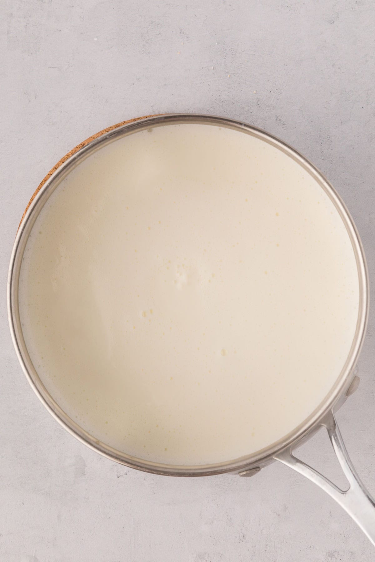 A smooth mixture of half and half and water heating in a stainless steel pot