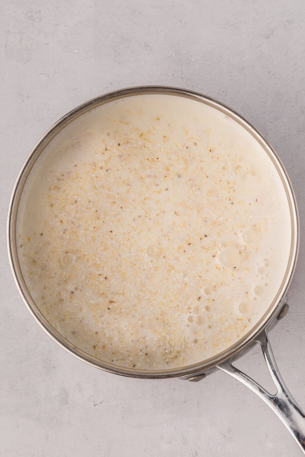 Dry grits stirred into the hot liquid mixture, beginning to cook