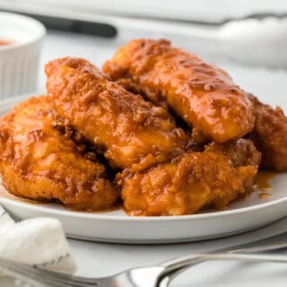 A plate of hot honey chicken in a white background