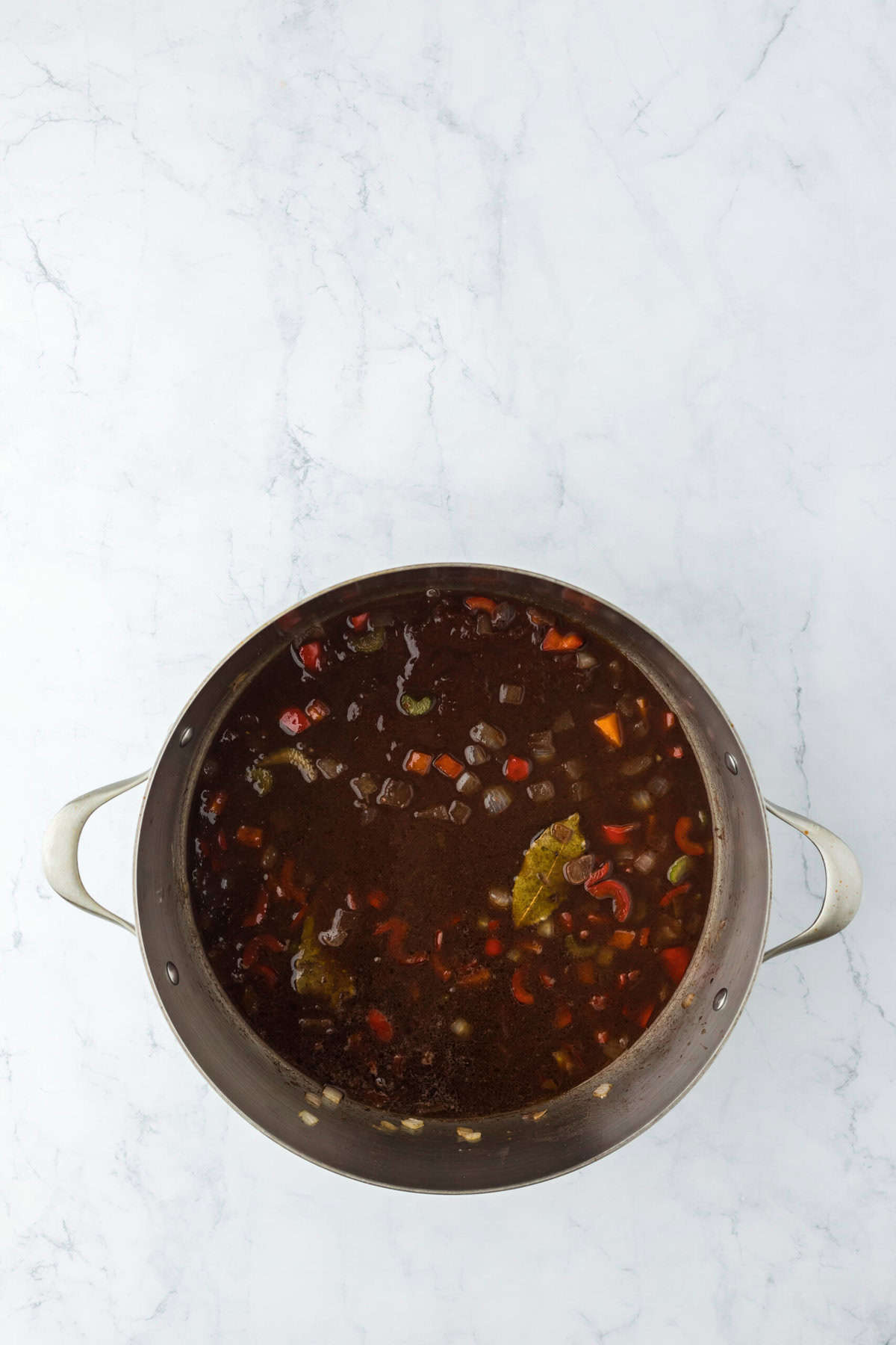 Red wine in veggies cooking in a pot on white background