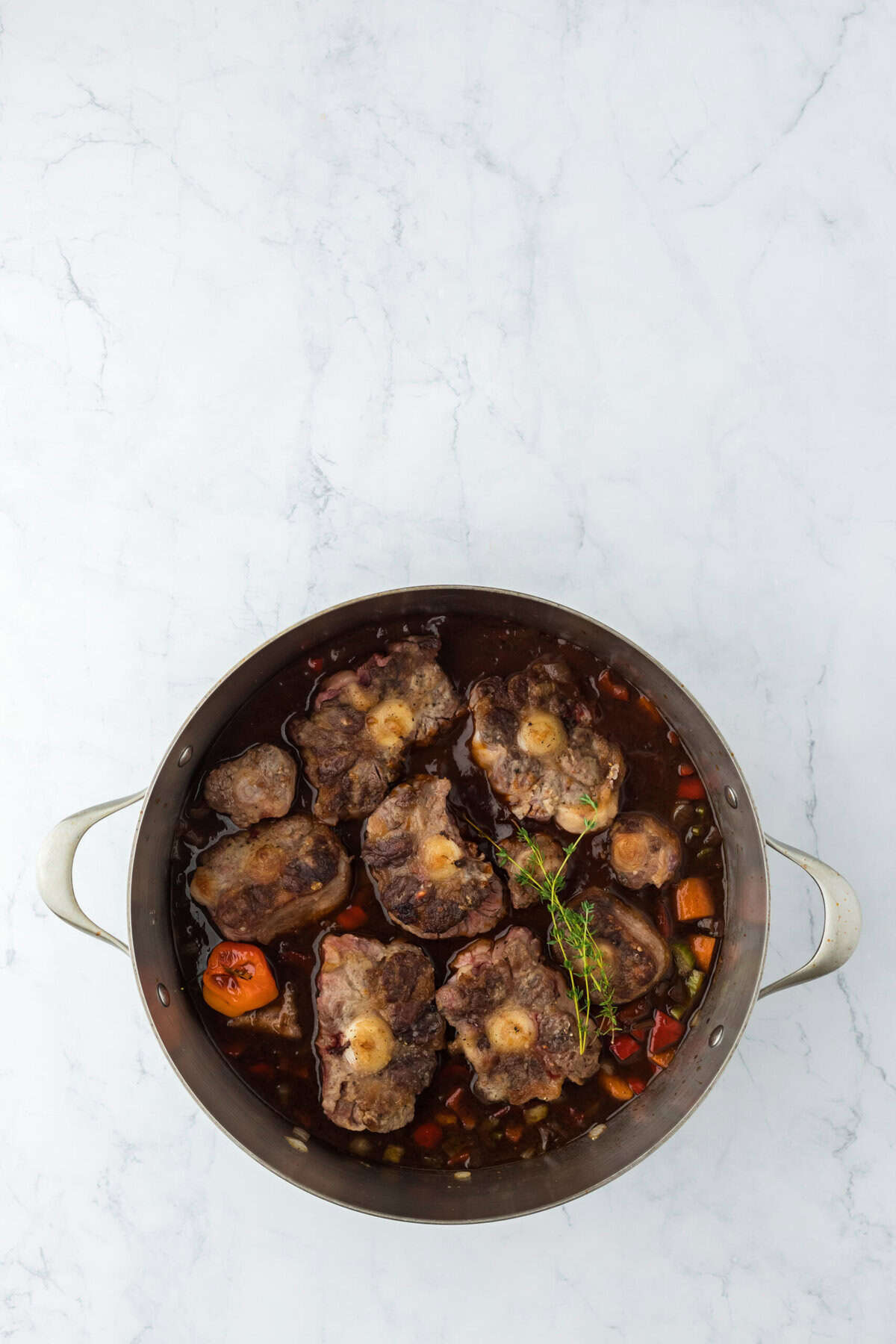 Jamaican oxtails in a broth and jerk sauce in a pot on white background