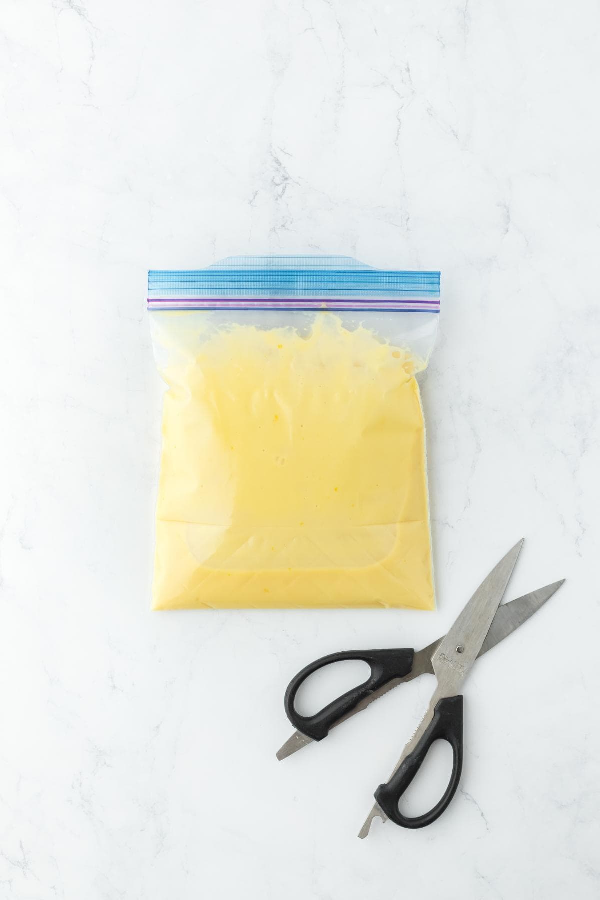 A zip-top bag filled with key lime filling next to a pair of scissors