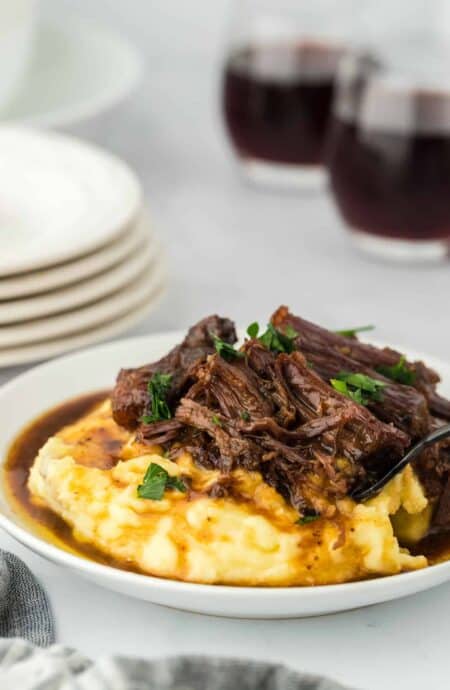 A large plate of a slow cooker Mississippi pot roast ready to serve over mashed potatoes
