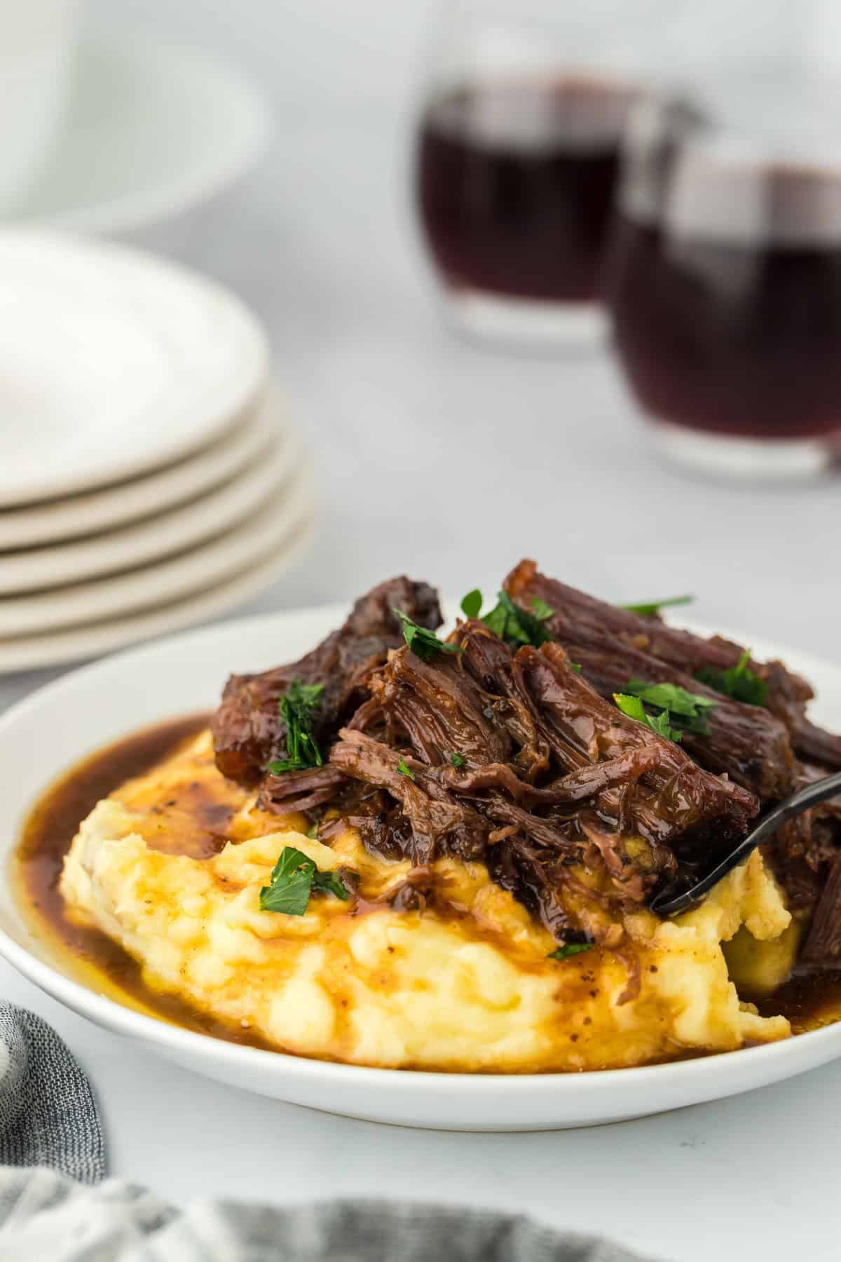 A large plate of a slow cooker Mississippi pot roast ready to serve over mashed potatoes