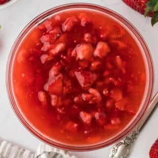 strawberry sauce against white background with fresh strawberries lying around