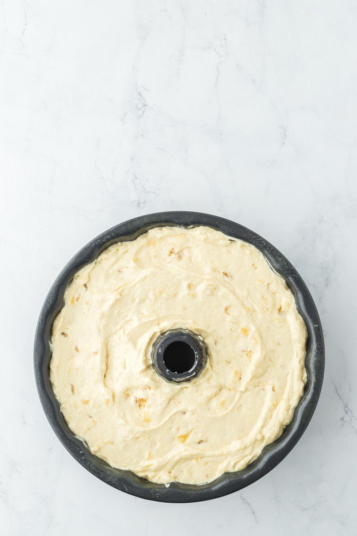 Pineapple pound cake batter spread in Bundt pan