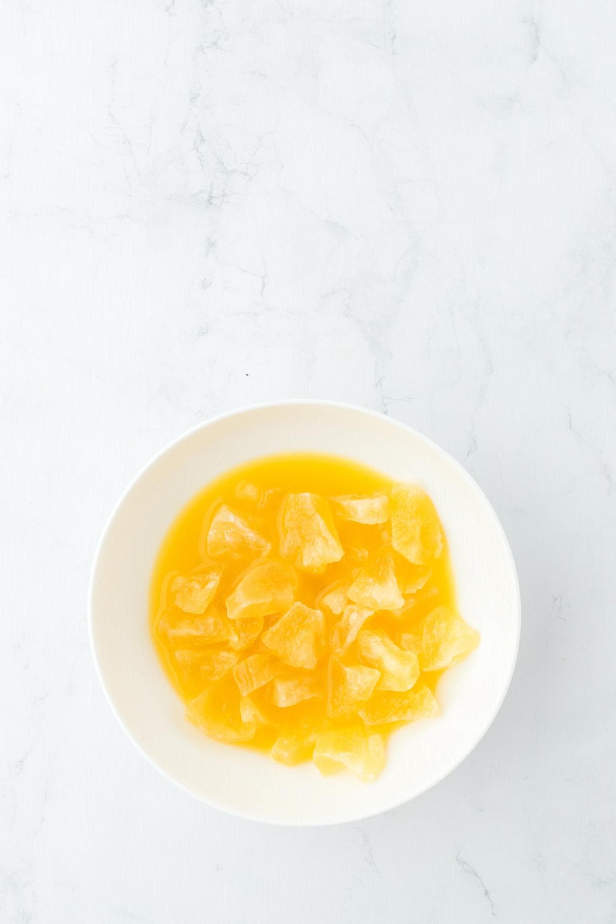 Crushed pineapple in bowl with orange juice