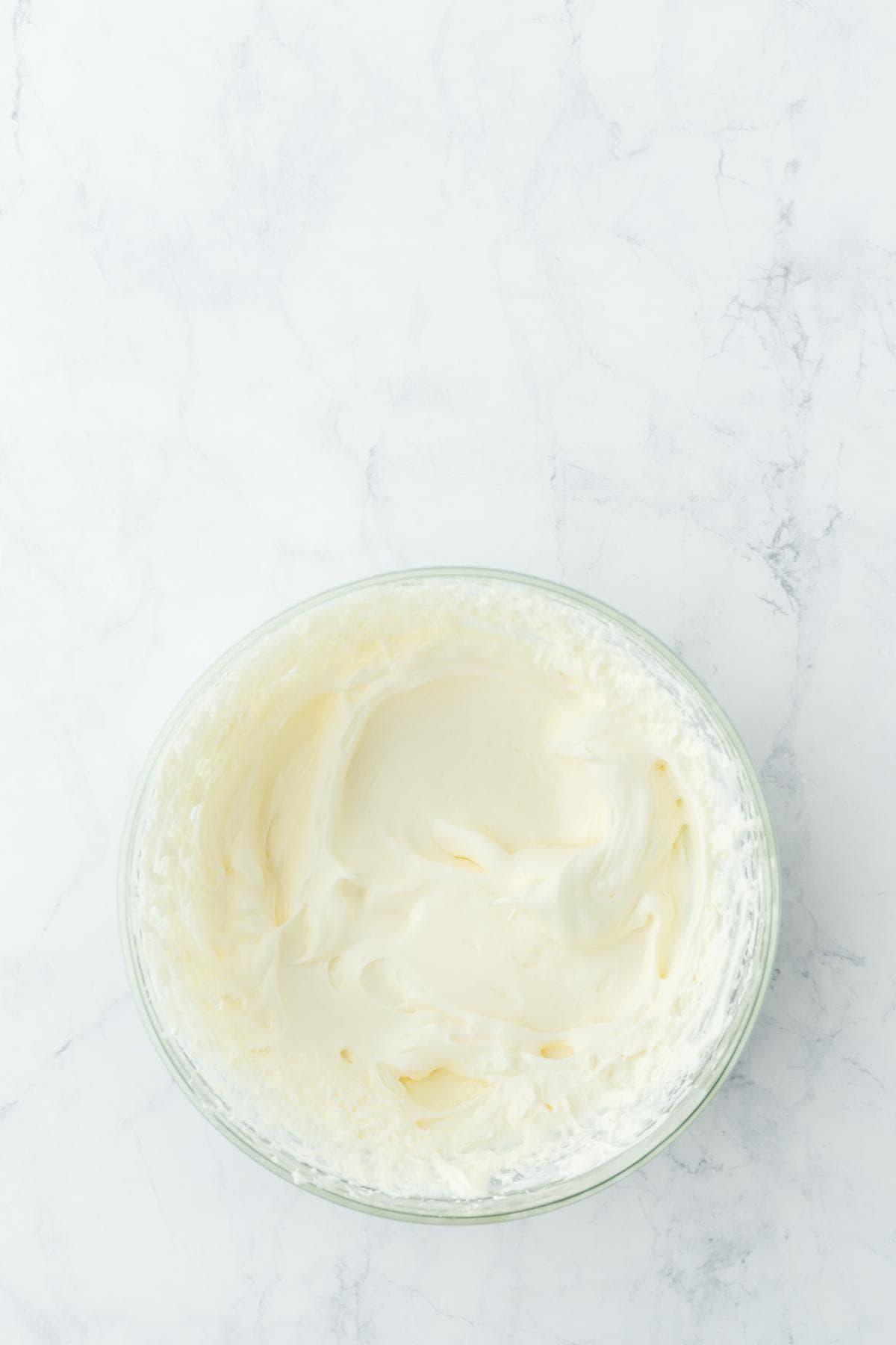 Whipped cheesecake topping fully mixed in a glass bowl