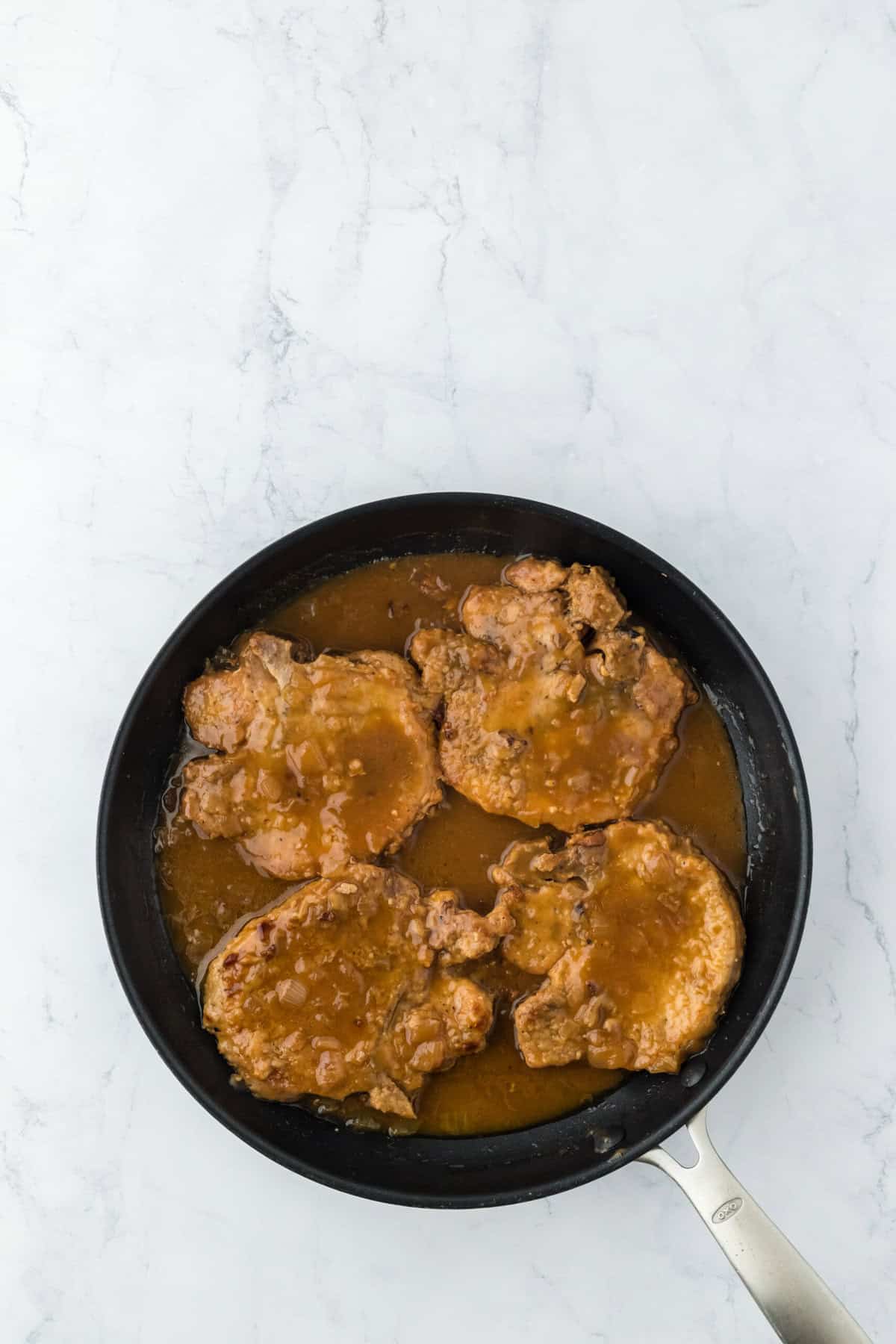 Completed smothered pork chops in a skillet ready to serve