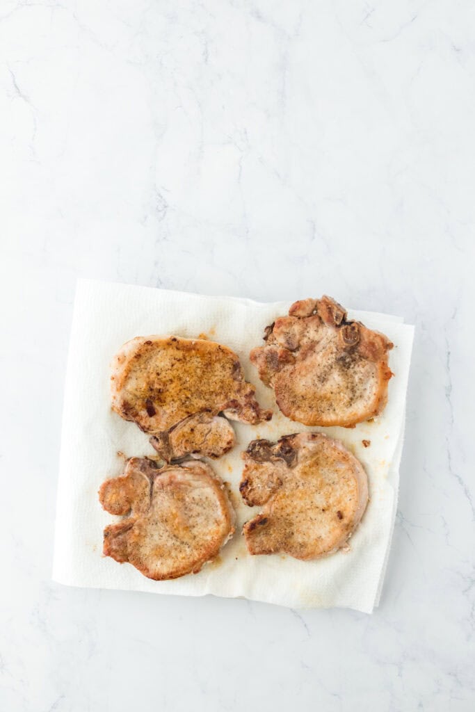 Fried pork chops being drained on paper towels