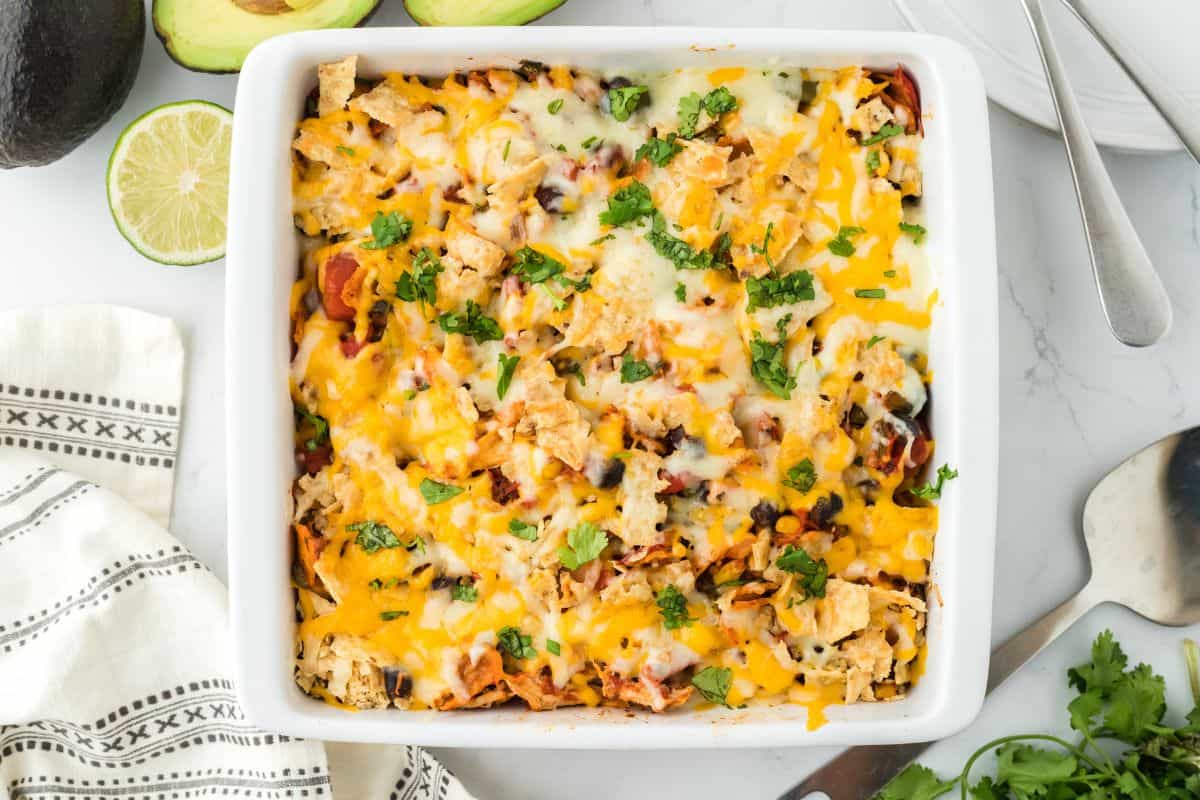 Overhead shot of a white rectangular baking dish filled with Southwestern chicken casserole, topped with melted cheese and chopped fresh cilantro