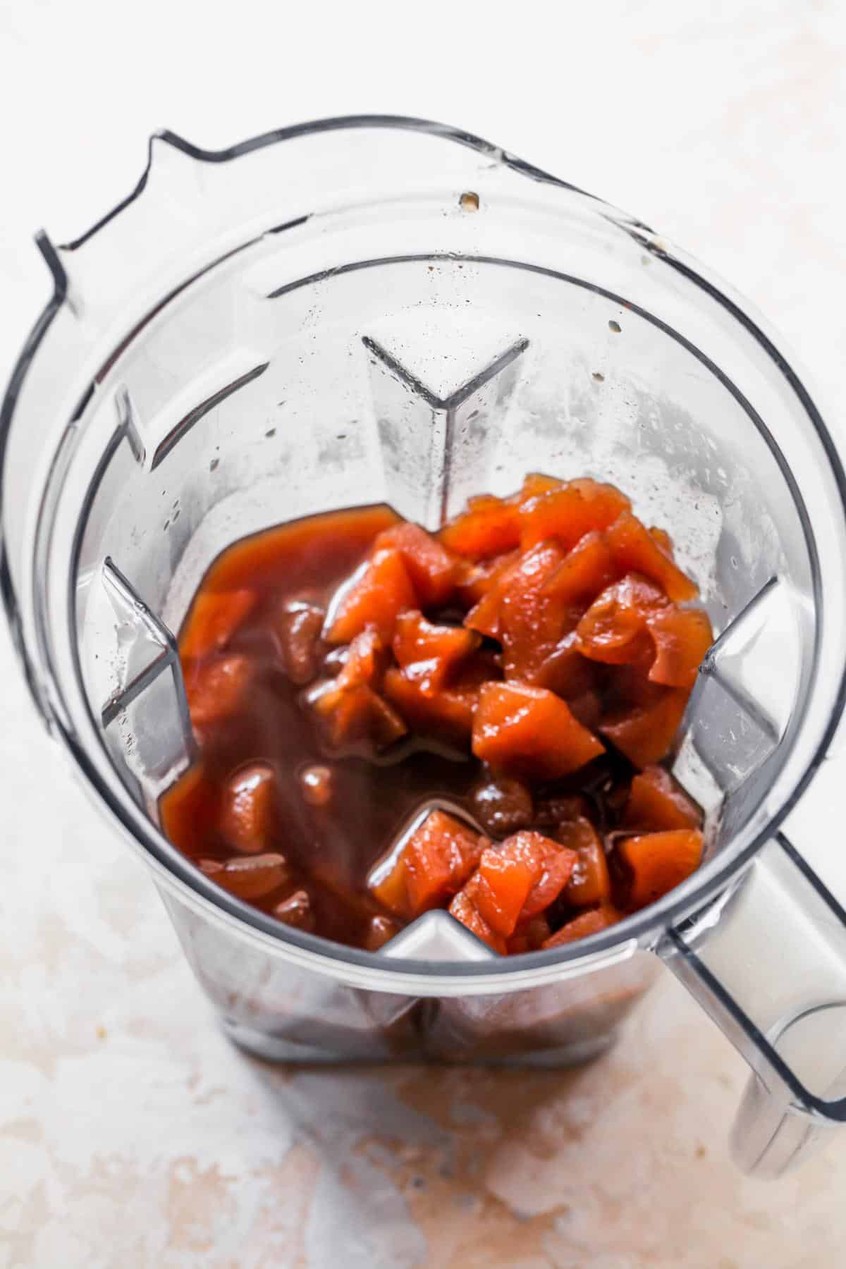 Cooked, diced apples in a reddish-brown syrup inside a blender, ready to be pureed