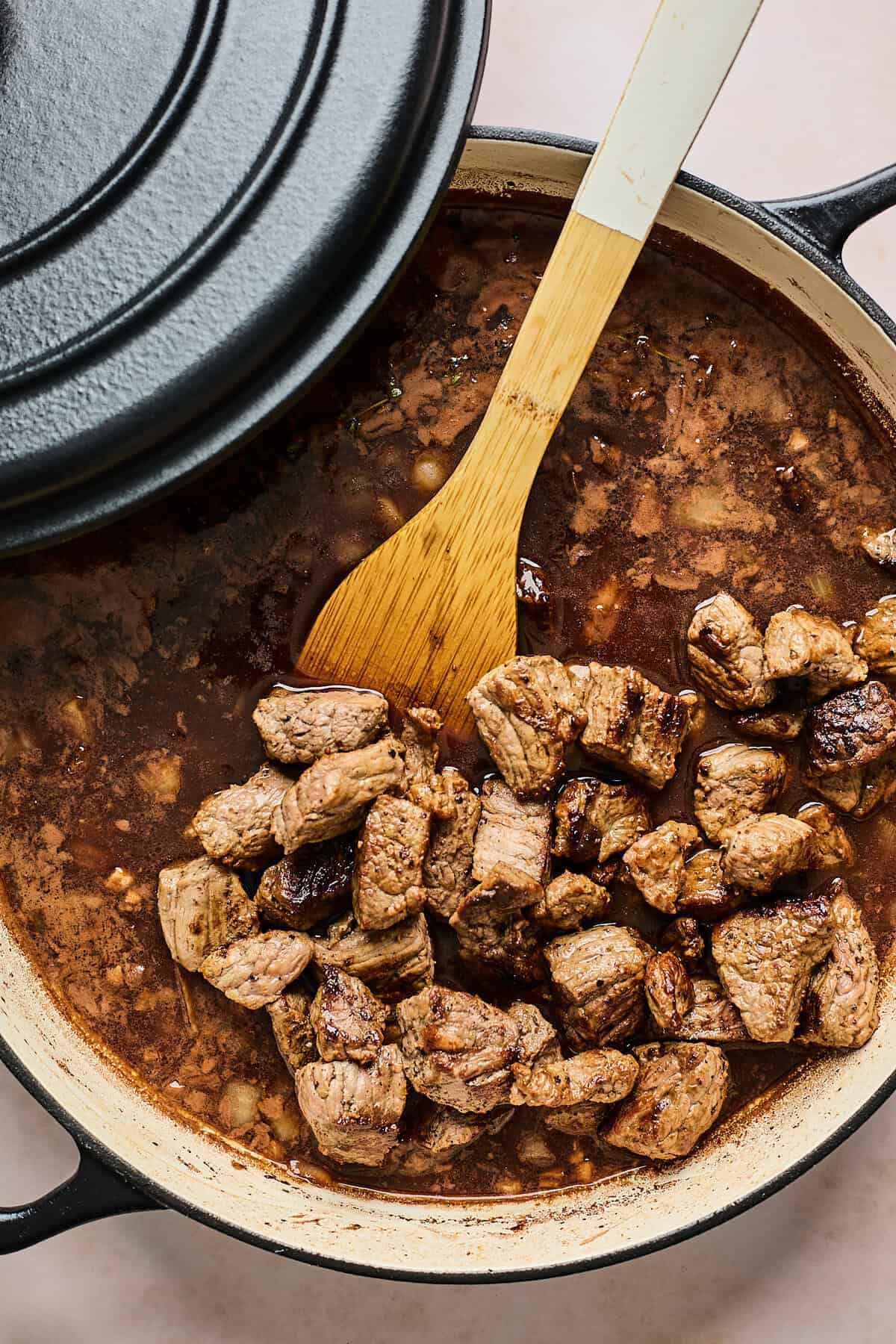 Tips of beef being added back into a gravy being stirred