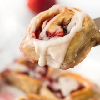 An easy strawberry cinnamon roll on a paddle ready to serve