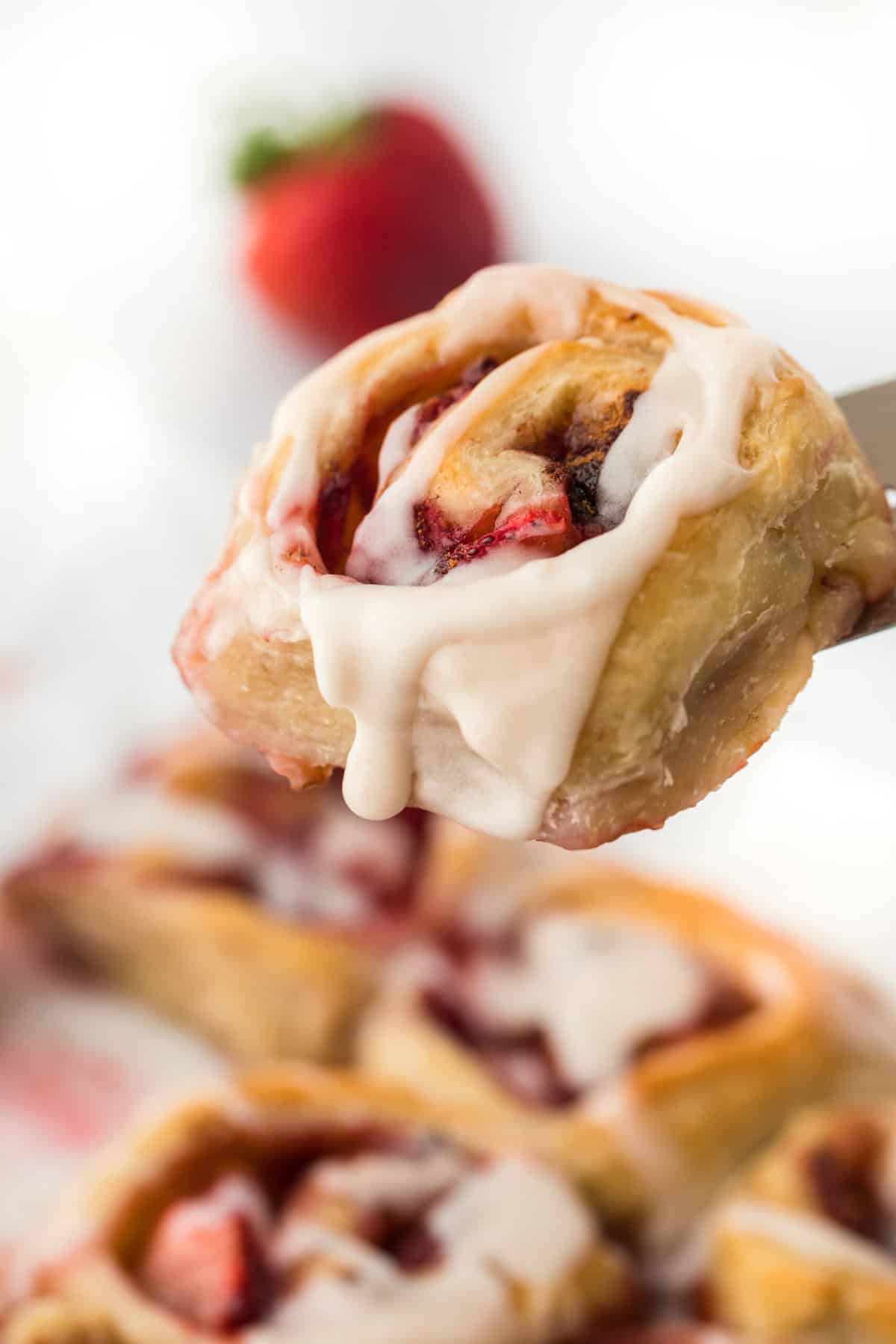 A close up of one easy strawberry cinnamon roll made with puff pastry with others in the background