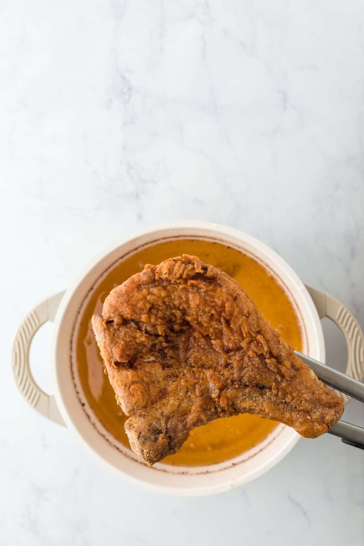 Close up of fried pork chop coming out of oil