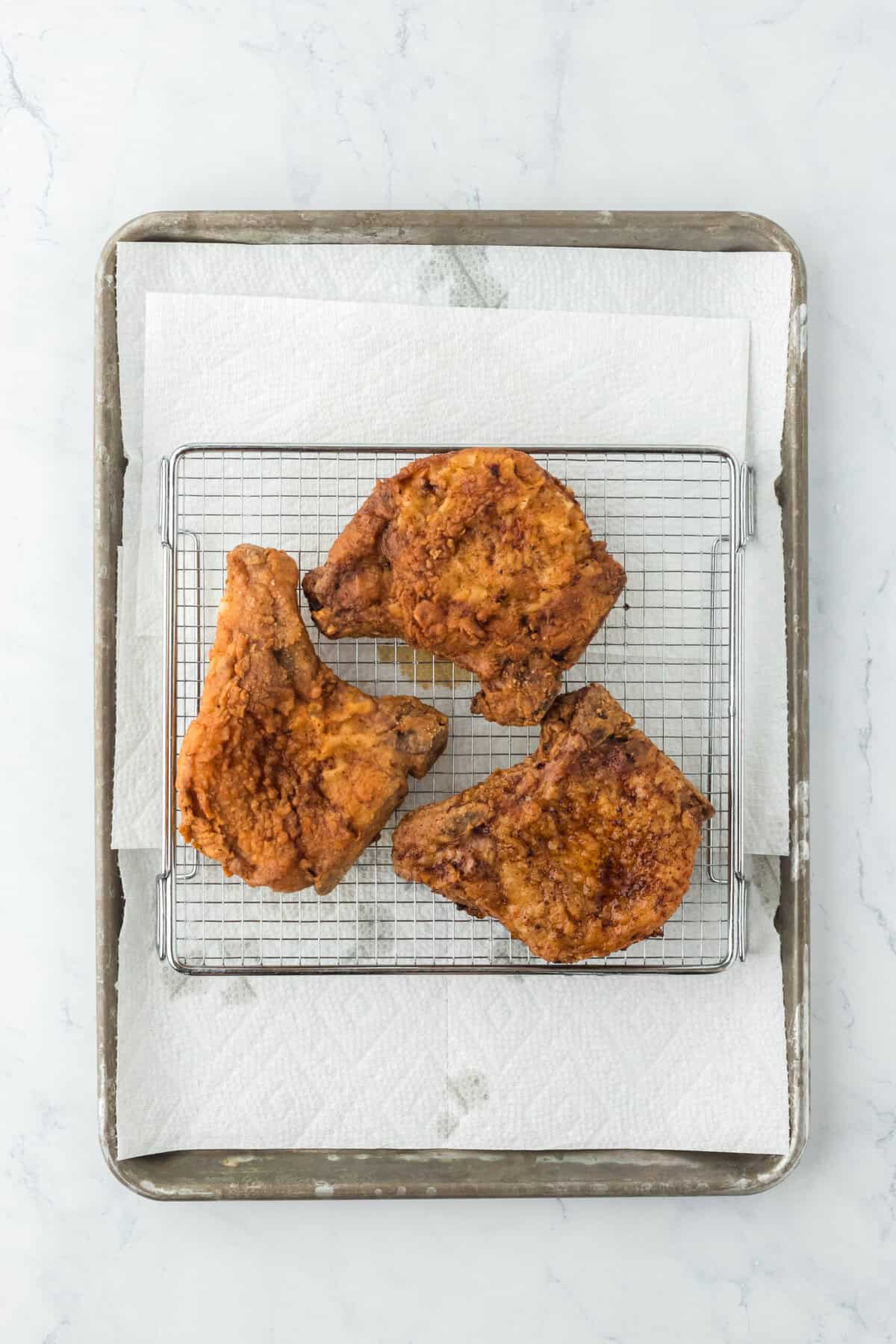 Fried pork chops on wire rack draining