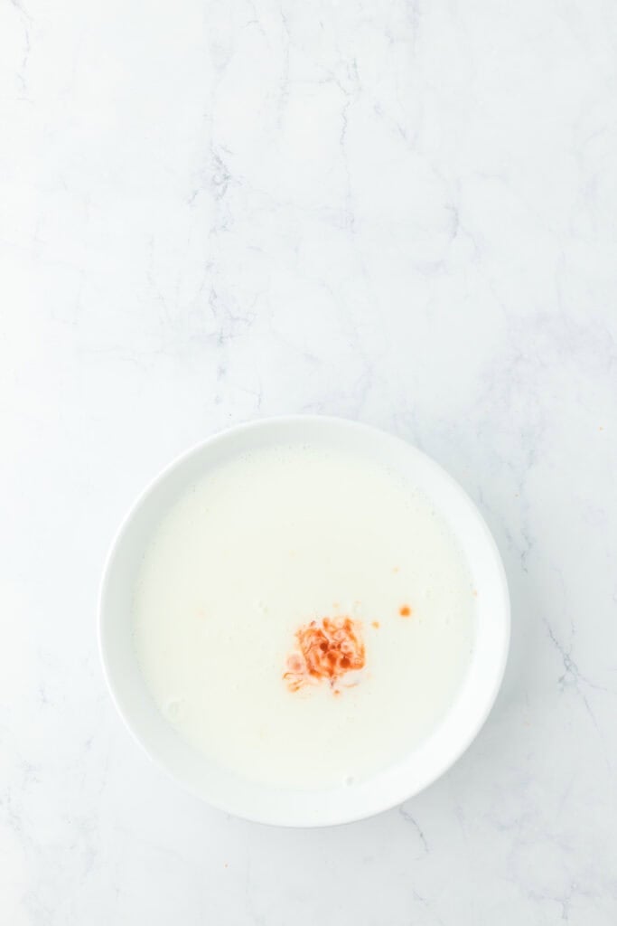 Buttermilk with hot sauce in a white bowl on white countertop