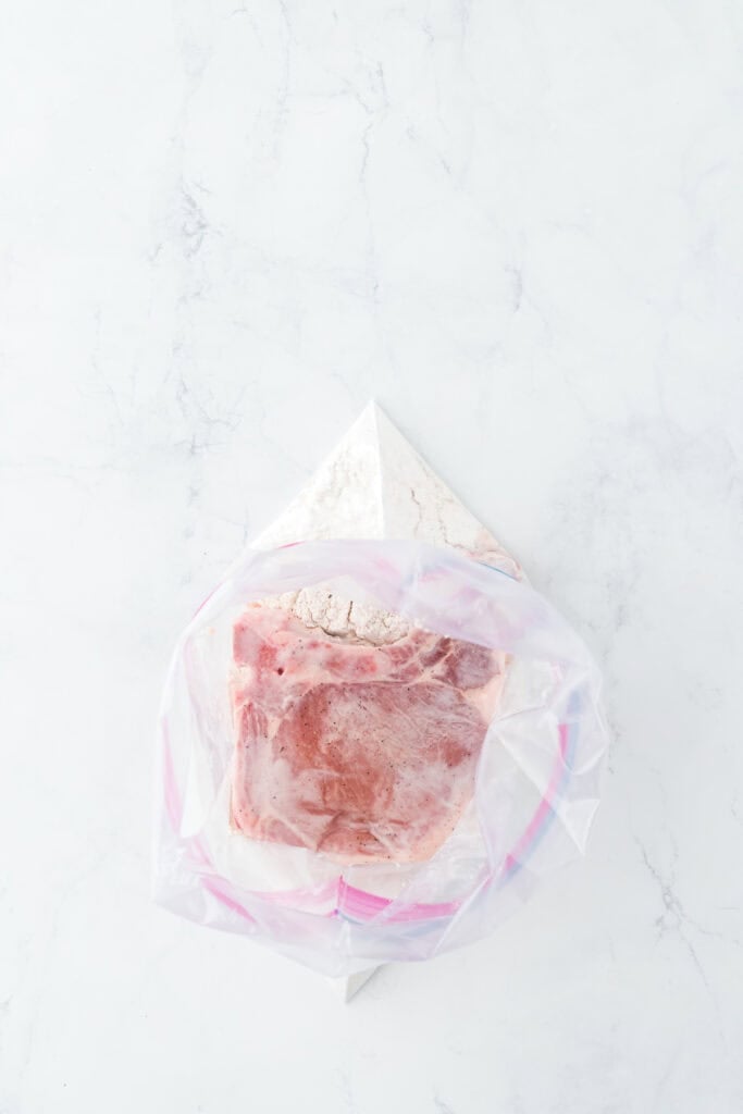 Marinated pork chops in seasoned flour in a ziptop bag